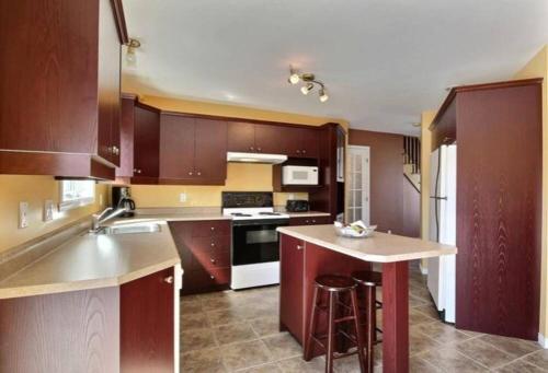 a kitchen with brown cabinets and a counter top at Lovely cottage with heated swimming pool in Quebec City