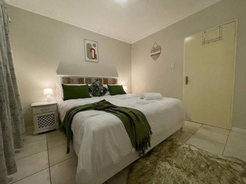 a bedroom with a large white bed with green pillows at Arabella By The Sea in Port Alfred