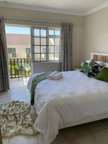a bedroom with a large white bed and a balcony at Arabella By The Sea in Port Alfred