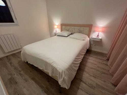 une chambre avec un grand lit blanc et deux lampes dans l'établissement Le Parc, T3 climatisé, Parking, Piscine, à Carcassonne