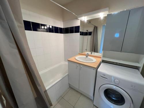 une salle de bain avec une machine à laver et un lavabo dans l'établissement Le Parc, T3 climatisé, Parking, Piscine, à Carcassonne
