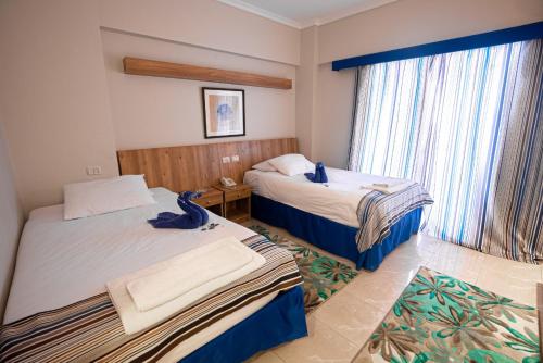 um quarto de hotel com duas camas e uma janela em New Siesta M Hotel em El Alamein