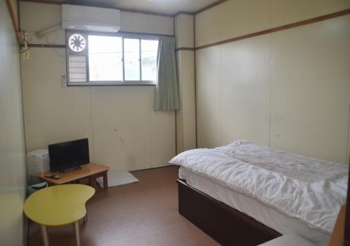Schlafzimmer mit einem Bett, einem Schreibtisch und einem Fenster in der Unterkunft Guest House Minatoya Tokunoshima - Vacation STAY 01034v in Tokunoshima