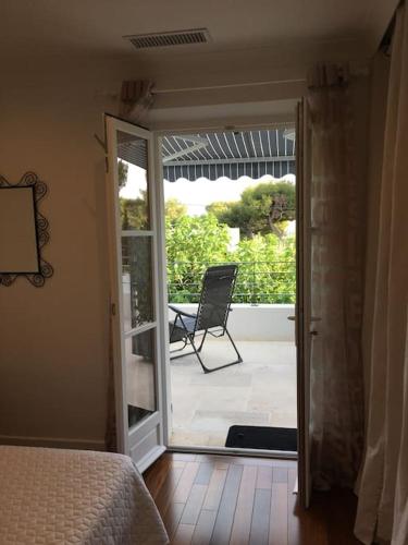 a bedroom with a door open to a patio with a chair at Cassis Calanques, 2 pièces grande terrasse vue mer in Cassis