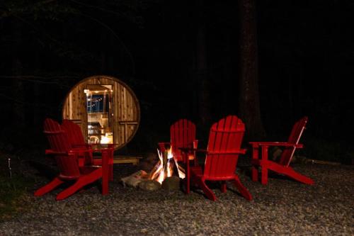 a group of chairs and a fire in front of a cabin at Pocono Mountain Retreat with Hot Tun and Sauna in Greentown