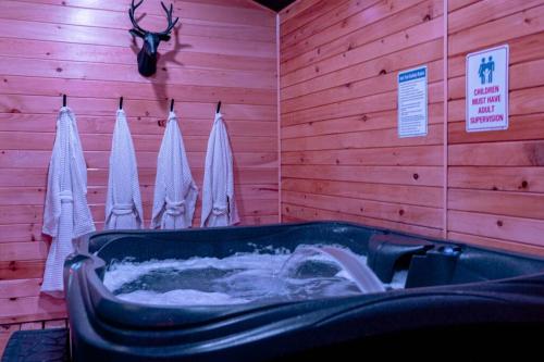 a bathroom with a tub and towels hanging on a wall at Pocono Mountain Retreat with Hot Tun and Sauna in Greentown