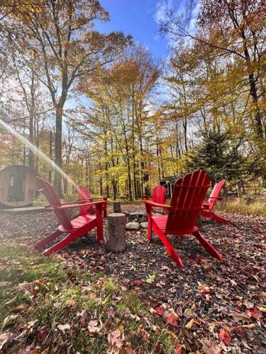 two red chairs sitting in the leaves in a park at Pocono Mountain Retreat with Hot Tun and Sauna in Greentown