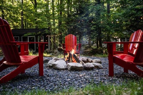 a fire pit with two red chairs in front of it at Pocono Mountain Retreat with Hot Tun and Sauna in Greentown