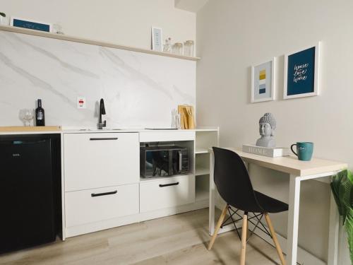 a white kitchen with a desk and a microwave at Apê Metrô Higienópolis Mackenzie in Sao Paulo