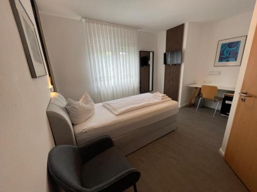 um pequeno quarto com uma cama e uma cadeira em Hotel Loewen em Tübingen
