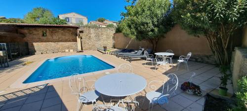 un patio con mesa, sillas y piscina en La Vernassonne, en Alzonne