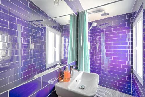 La salle de bains est pourvue de carrelage bleu, d'un lavabo et d'une fenêtre. dans l'établissement St André 4G - Best Location, à Paris