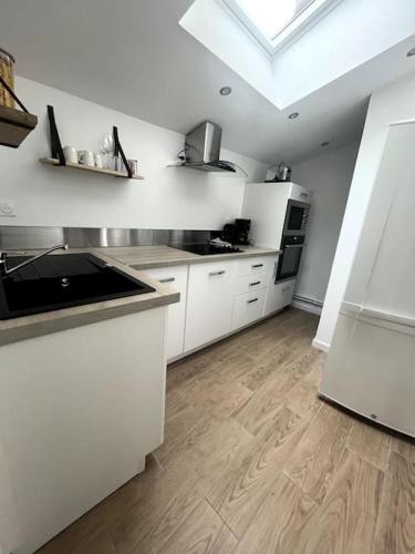 une cuisine avec des armoires blanches et un plancher en bois dans l'établissement chez Corinne, à Bray-Dunes
