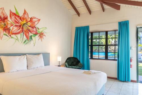 a bedroom with a bed and a flower painting on the wall at Talk of the Town Inn & Suites - St Eustatius in Oranjestad