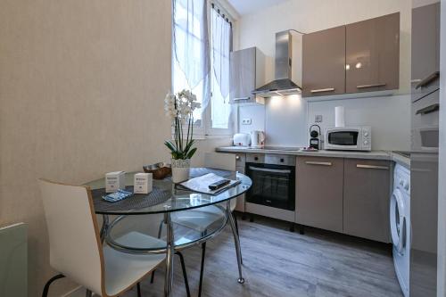 une cuisine avec une petite table et une cuisine avec un four micro-ondes dans l'établissement Cosy Eugénie au pied de l'Opéra et du Kiosque, à Vichy