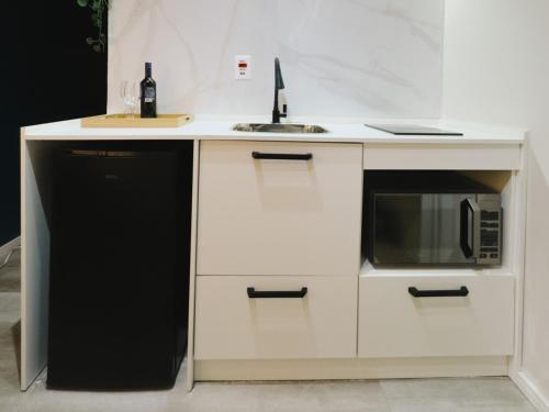 a white kitchen with a sink and a microwave at Apê Metrô Higienópolis Mackenzie in Sao Paulo