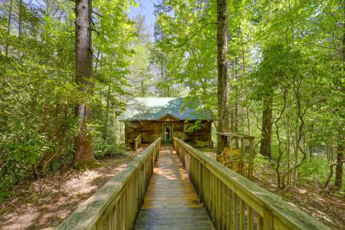 a bridge leading to a cabin in the woods at Near Lake Lure Quiet Cabin with Deck and Trail Access in Marion