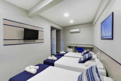 a room with four beds and a flat screen tv at Hotel Marjaí in Itajaí