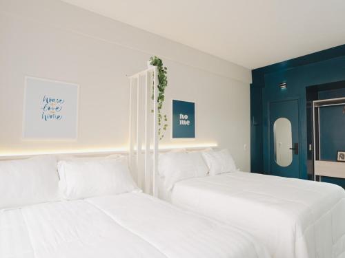 two white beds in a room with blue walls at Apê Metrô Higienópolis Mackenzie in Sao Paulo
