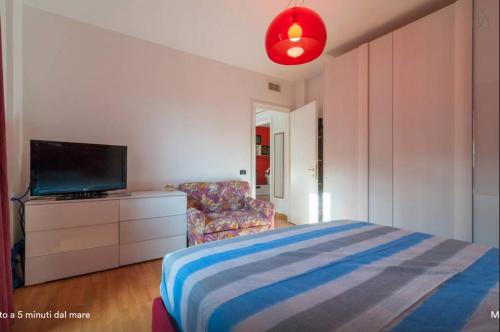 Schlafzimmer mit einem Bett, einem TV und einem Stuhl in der Unterkunft Giuseppe's House in Monserrato