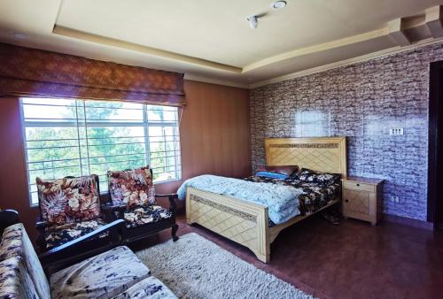 a bedroom with a bed and a couch and a window at Drowned in Clouds V2 in Nathia Gali
