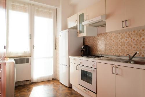 uma cozinha com armários brancos e um lavatório em La Casa di Merion em Posatora