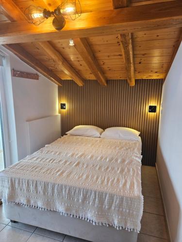 sypialnia z łóżkiem i drewnianym sufitem w obiekcie Pantheon Attic w mieście Alonissos-Chora