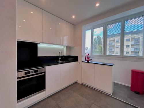 eine Küche mit weißen Schränken und einem großen Fenster in der Unterkunft Appartement moderne et lumineux in Charenton-le-Pont