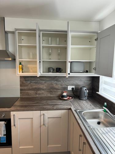 Una cocina con gabinetes blancos y un fregadero. en Inchmoan Apartment, en Bonhill