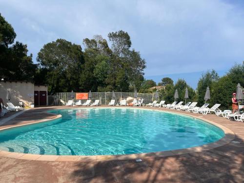 une grande piscine avec des chaises dans l'établissement Mini Villa 63 proche plage dans résidence avec piscine à Favone, à Sari-Solenzara