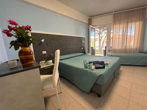 a bedroom with a bed and a table with a vase of flowers at Hotel Monna Lisa in Procchio