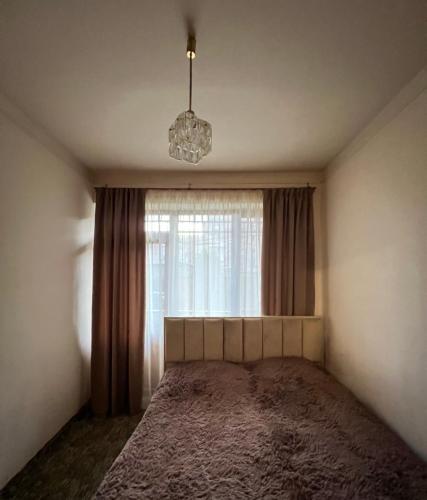 a bedroom with a bed with a window and a chandelier at Anahit's Apartment in Vagharshapat