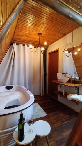 a bathroom with a tub and two sinks in a room at Chalé romântico São Bento do Sapucaí - Jacuzzi - Chalé Gênova in São Bento do Sapucaí