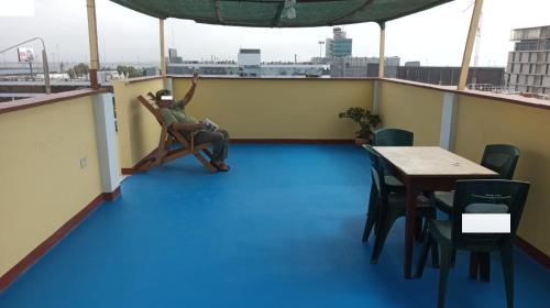 un hombre sentado en una silla en un balcón con una mesa en "A y J Familia Hospedaje" - Free tr4nsfer from the Airport to the Hostel en Lima