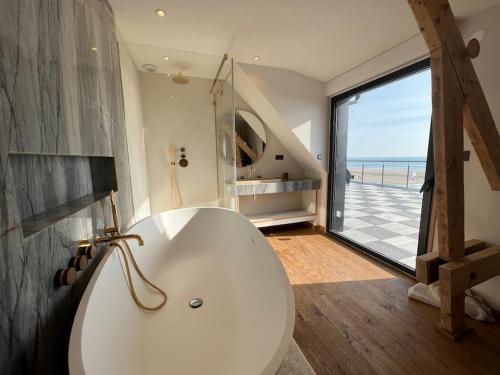 une grande baignoire blanche dans une salle de bain avec vue sur l'océan dans l'établissement Le Sémaphore, à Saint-Germain-sur-Ay