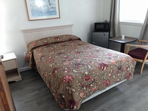 a bedroom with a bed with a floral bedspread at Eldorado Motel, New Castle in New Castle