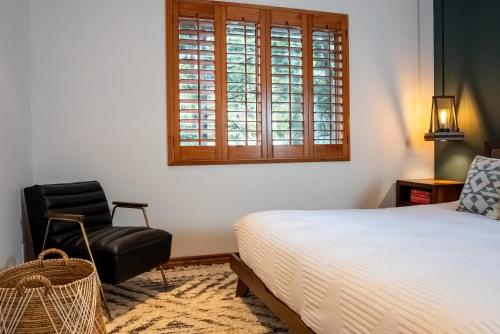 a bedroom with a bed and a chair and a window at The Mighty Pines Retreat + Large Patio + BBQ+View! in Lake Arrowhead
