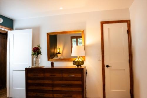 a bedroom with a dresser with a mirror and a lamp at The Mighty Pines Retreat + Large Patio + BBQ+View! in Lake Arrowhead