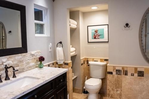 a bathroom with a toilet and a sink and a mirror at The Mighty Pines Retreat + Large Patio + BBQ+View! in Lake Arrowhead
