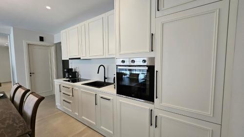 a kitchen with white cabinets and a black appliance at Kooba Villas in Gázion