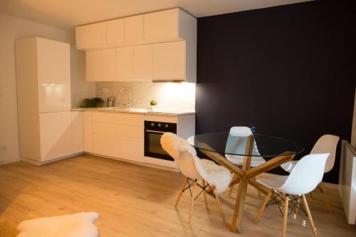 une cuisine avec une table en verre et des chaises blanches dans l'établissement Appartement Terrasse Jardin à 2 pas de la plage, à Wissant