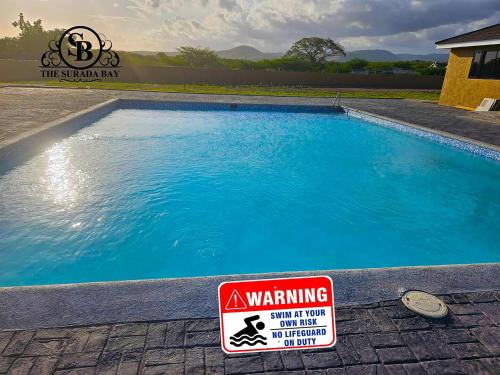 uma piscina com um sinal de aviso ao lado em The Surada Bay em Old Harbour