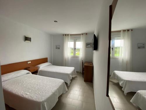 a hotel room with four beds and a mirror at Hotel Chiquín in Tapia de Casariego