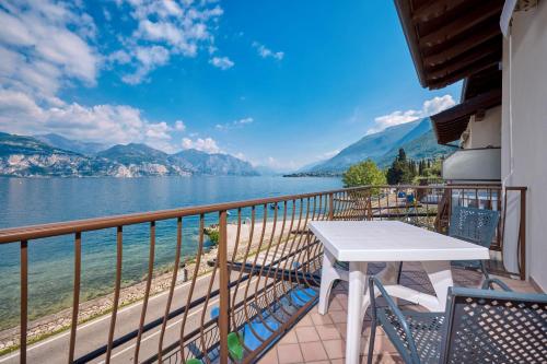 balcón con mesa y vistas al agua en Locanda Bellavista food&rooms en Malcesine