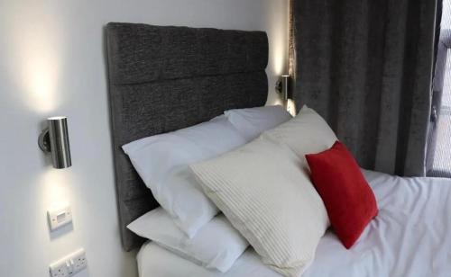 Una cama con almohadas blancas y rojas. en Kick back relax stylish space en Nottingham
