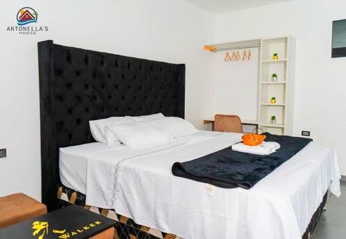 a bedroom with a large bed with a black headboard at ANTONELLA'S House in Huanchaco