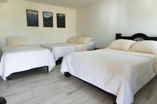 a bedroom with two beds with white sheets at Colina del Sol Hotel Hacienda in Quimbaya