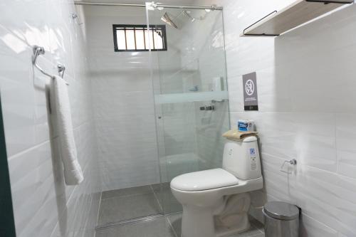 a bathroom with a toilet and a glass shower at Colina del Sol Hotel Hacienda in Quimbaya