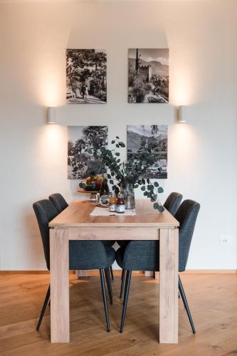 a dining room table with chairs and paintings on the wall at Promenaden Lounge in Merano