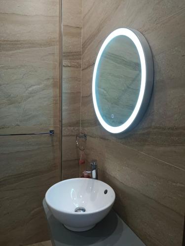 a bathroom with a white sink and a round mirror at enjoy your holidays with us in Attard